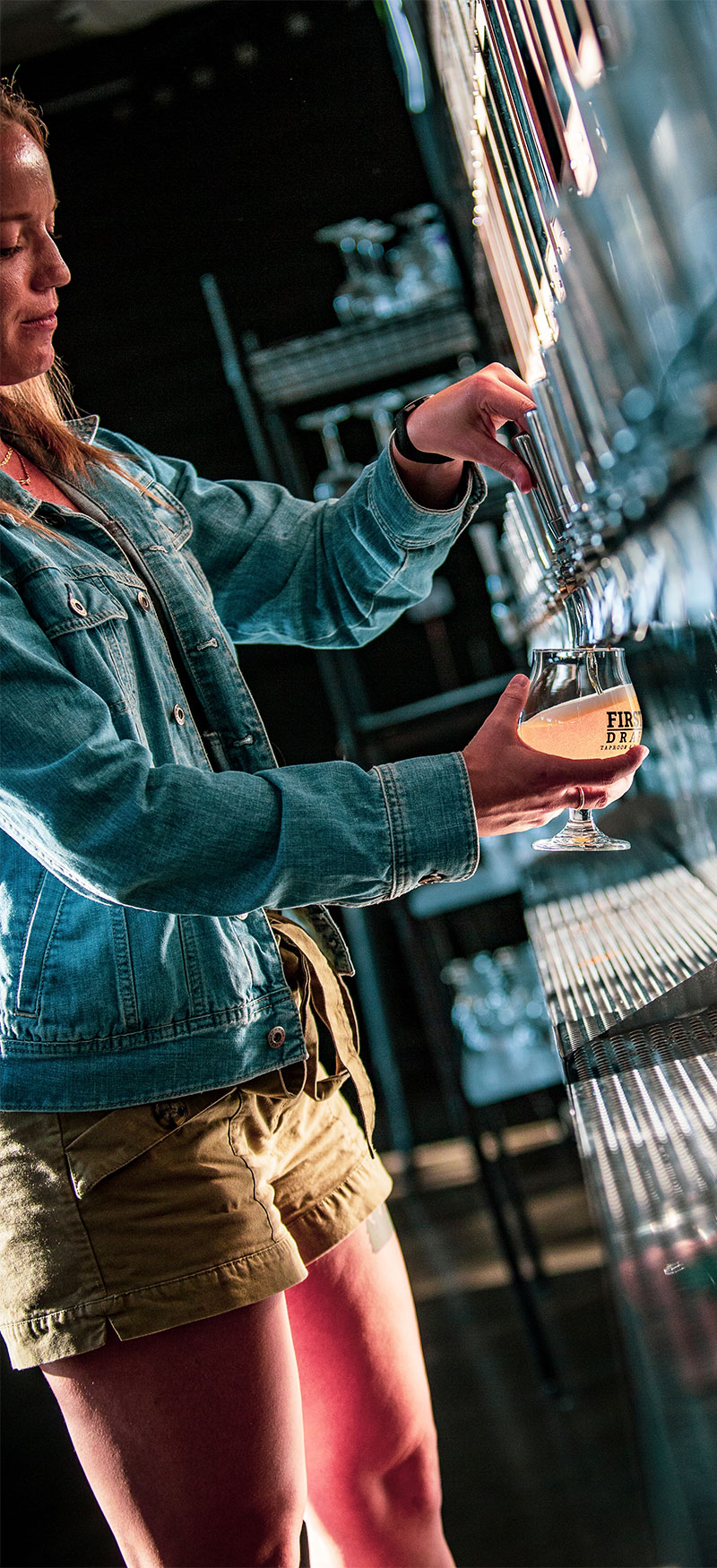 Woman filling her beer glass using a self-service tap